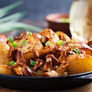 Baked potatoes with garlic, herbs and fried chanterelles in a cast iron skillet.