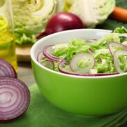 Savoy cabbage and onion salad served in bowl on wooden table