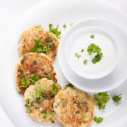 Cabbage pancakes with parsley and yogurt dressing on a white plate. Top view